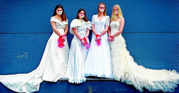 Vier Mädchen in weißen Hochzeitskleidern, ihre Münder mit weißem Band zugeklebt